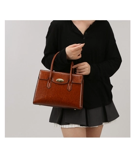 Detail of vintage brown leather handbag with gold oval twist lock and sturdy top handles