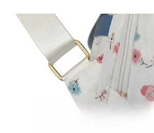Detailed close-up of golden metal D-ring hardware on floral lace backpack straps