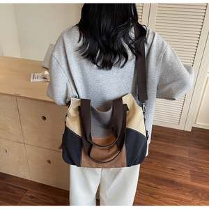 Lifestyle shot of large color-block canvas tote bag with brown shoulder strap worn by model