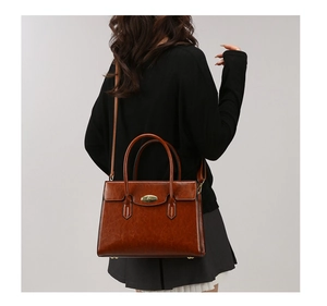 Detail of a brown oil wax leather tote bag with vintage metal lock and top handles