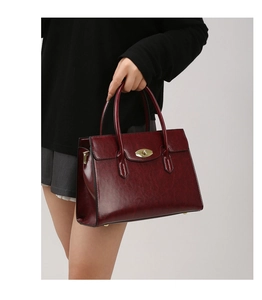 Detail of burgundy vintage leather handbag with a gold oval twist lock and retro texture