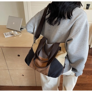 Lifestyle view of a large color-block canvas tote bag with wide straps for daily commute