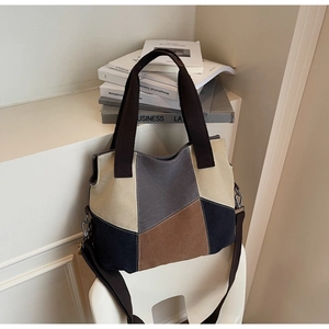 Detail of color-block canvas tote bag with adjustable brown strap on a white chair