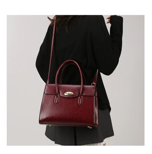 Side view of model wearing a wine red oil wax leather handbag with golden metal lock