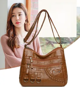 Detailed macro view of brown woven PU leather crossbody bag with multiple zipper pockets