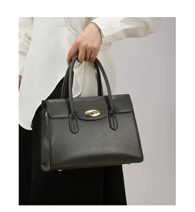 Detail of dark grey leather handbag showing the elegant gold oval twist lock and fine stitching
