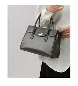 Detail of dark grey leather handbag showing golden oval twist lock and craftsmanship