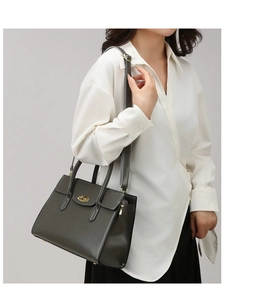 Detail of olive green leather handbag with gold oval twist lock and slim shoulder strap
