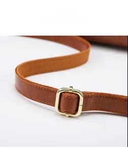 Close-up of brown leather shoulder strap with adjustable gold buckle and pebble texture