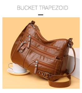 Dettaglio della borsa a secchiello marrone in pelle con zip multiple e fibbie metalliche