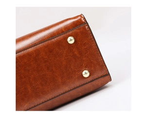 Close-up of brown oil wax leather bag bottom with gold rivets and black stitching detail