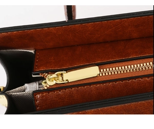 Macro shot of smooth gold zipper and stitching detail on caramel brown leather tote bag