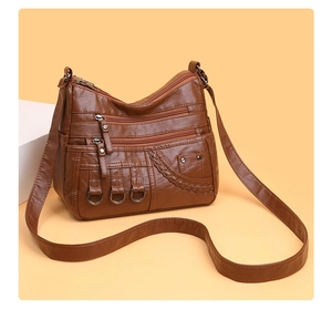 Detail of brown faux leather crossbody bag with multiple zippers and woven texture accents