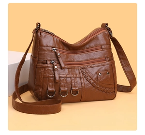 Detail of dark brown faux leather crossbody bag showing multiple zippers and woven texture