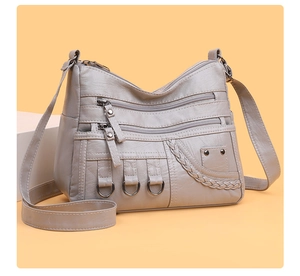 Detail of grey soft leather crossbody bag with metal zippers and woven texture design
