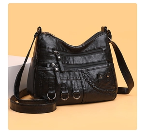 Detail of black woven PU leather crossbody bag featuring multiple metal zipper pockets
