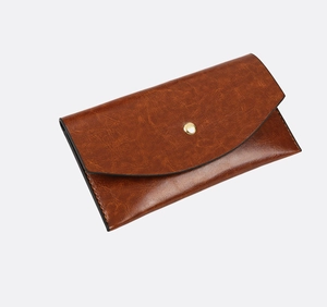 Detail of vintage brown leather envelope wallet with golden metal button closure