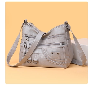 Detail of grey multi-pocket crossbody bag featuring litchi texture and silver hardware