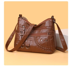 Detail of caramel faux leather bag featuring multiple front zip pockets and woven texture