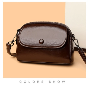 Detalle de bolso bandolera de cuero brillante marrón oscuro con cremallera y costuras