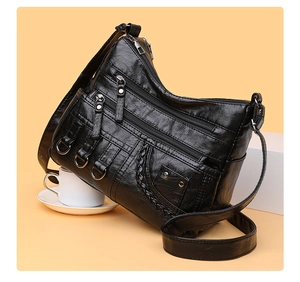 Detail of black woven crossbody bag featuring three front zippers and litchi texture PU leather