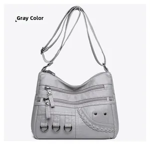 Close-up of a gray woven shoulder bag featuring multiple zippers and metallic details