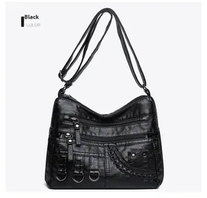 Detail of black woven PU leather crossbody bag featuring multiple zipper pockets and metal ring