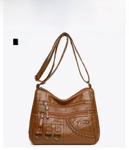 Front view of brown vintage leather crossbody bag with multi-layer zippers and woven detail