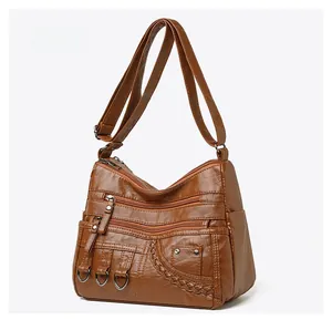 Detail of brown woven faux leather crossbody bag with multiple front zipper pockets