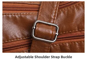 Detail of adjustable metal buckle and triple zipper on brown litchi texture leather bag
