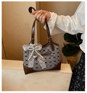 Close-up of women's bucket bag featuring lace bow, pearl charm and heart pendant detail