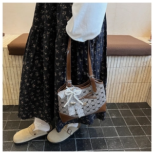 Detail of gingham bucket bag with lace bow, pearl accents and brown leather strap