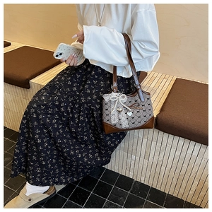 Detail of a chic bucket bag featuring lace bows, pearls, and heart charms on woven fabric