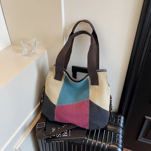 Multi-colored canvas tote bag with adjustable shoulder strap on black luggage suitcase