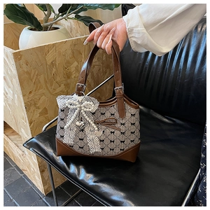 Detail of checkered bucket bag featuring white lace bow, pearls, and heart pendant