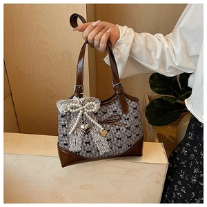 Detail of vintage plaid handbag with pearl lace bow and heart charm decoration