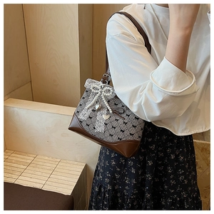 Detail of retro plaid shoulder bag with brown leather trim and lace pearl bow ornament