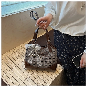 Detail of vintage brown leather handbag with houndstooth pattern and lace bow accessory