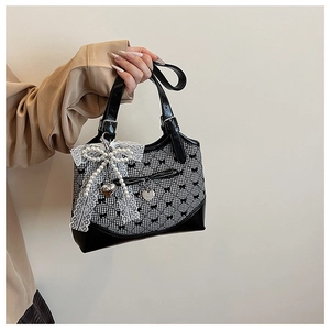 Detail of checkered handbag featuring pearl lace bow charms and silver heart pendant