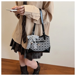 Detail of checkered shoulder bag with lace bow pendant and pearl accents in lifestyle setting