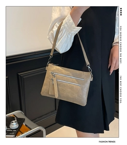 Detail view of khaki crossbody bag with double silver zippers and thin shoulder strap