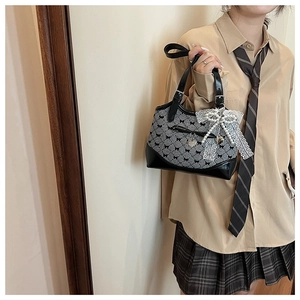Detail of preppy style handbag featuring heart charm and lace pearl bow ornament