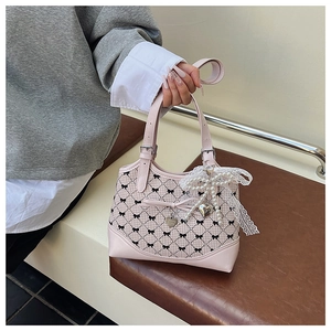 Pink plaid handbag with black bow prints and a lace pearl charm on a leather seat