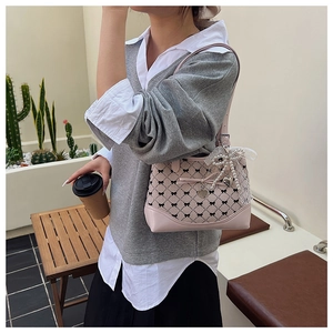Pink shoulder bag detail showing black bow patterns and lace pearl charm accessories