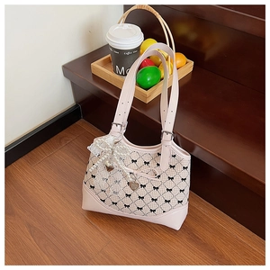 Detailed view of pink plaid bucket bag with black bow print and pearl lace charm on wooden stairs