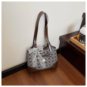 Close-up of black and white checkered bucket bag with lace bow and pearl charms