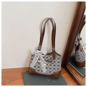 Detail of crossbody bucket bag featuring plaid fabric, lace bows, and pearl heart charms