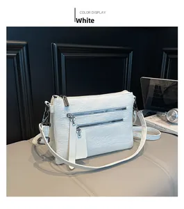 Detailed macro of white litchi grain leather crossbody bag with dual zipper pockets