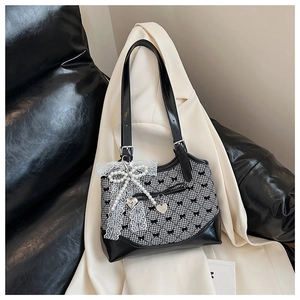 Detail of checkered weaving pattern with lace pearl bow and metal heart charm on the bag