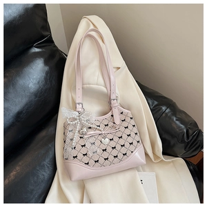 Detail of pink canvas bucket bag with black bow patterns and lace pearl heart charm